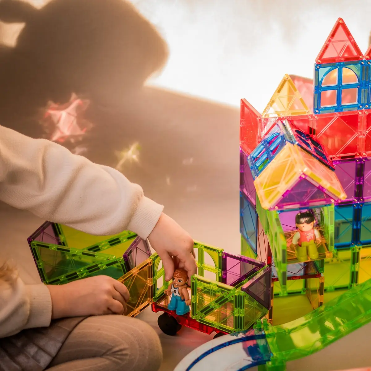 Kind bouwt een huis van magnetische tegels met een poppetje erin
