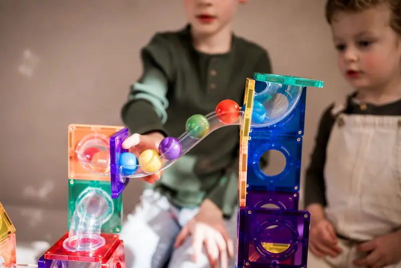 Kinderen kijken hoe knikkers door een magnetische knikkerbaan rollen