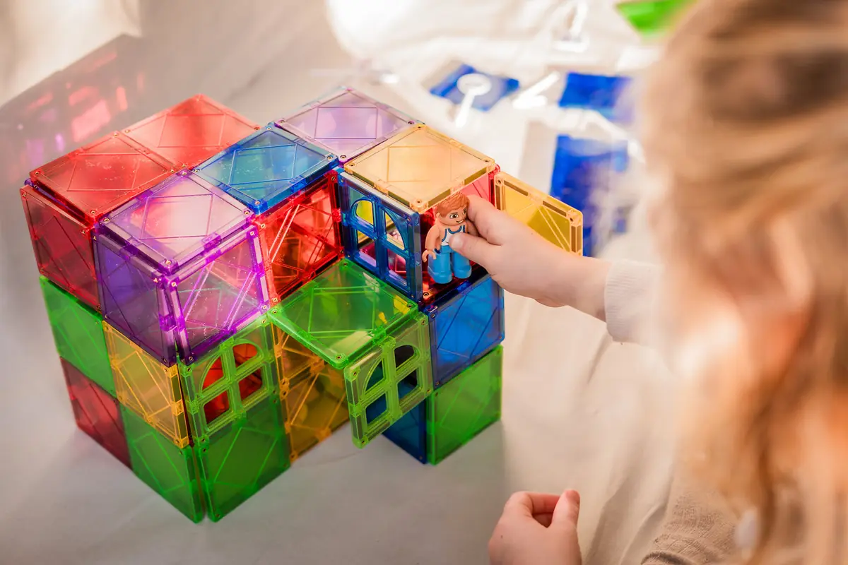 Kind bouwt kubussen van magnetische tegels