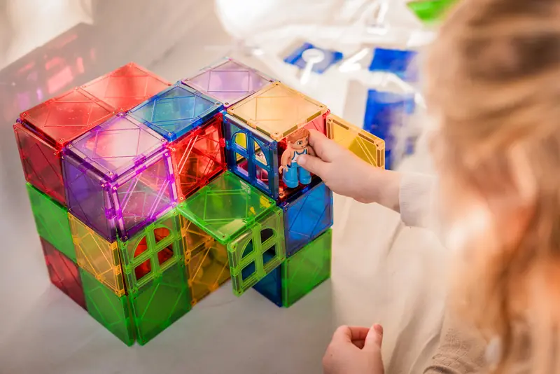 Kind bouwt kubussen van magnetische tegels
