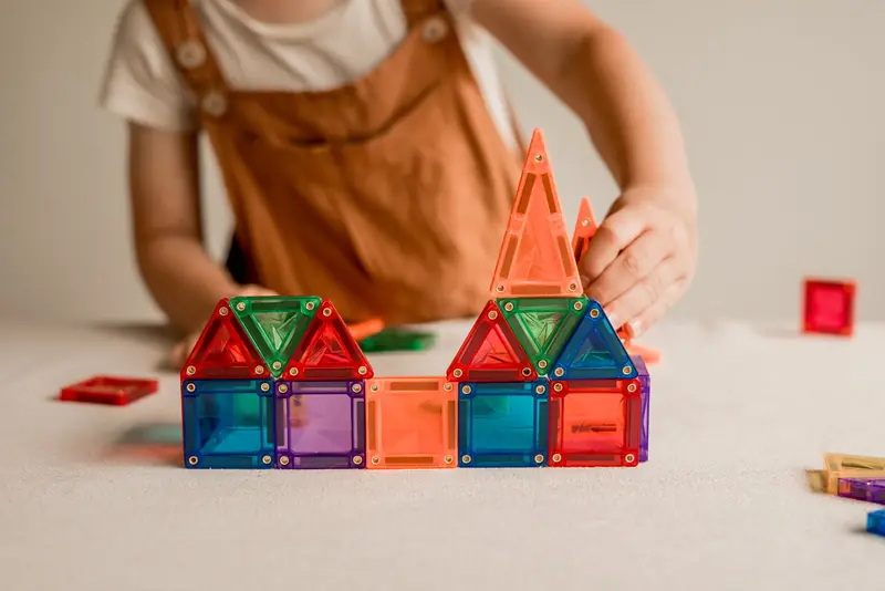 Kinderhanden bouwen een huisje van micro-tegels