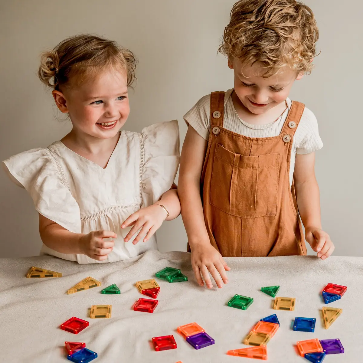 Twee peuters spelen lachend met micro-tegels