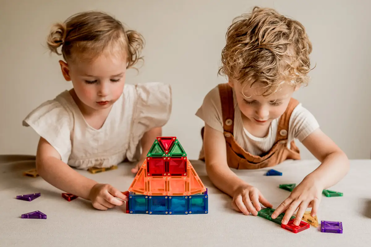 Twee peuters bouwen samen een huisje van magnetische tegels