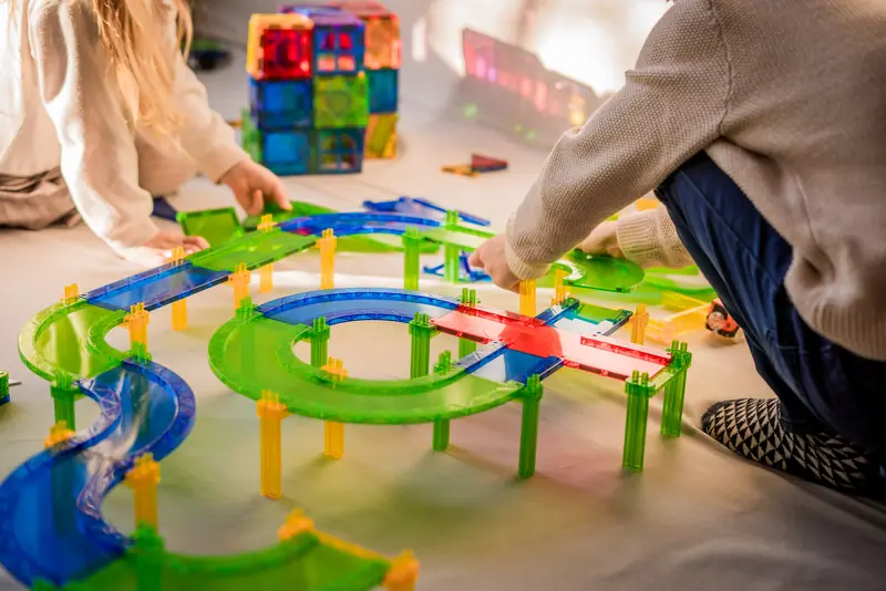 Kinderen spelen met een magnetische racebaan op de vloer